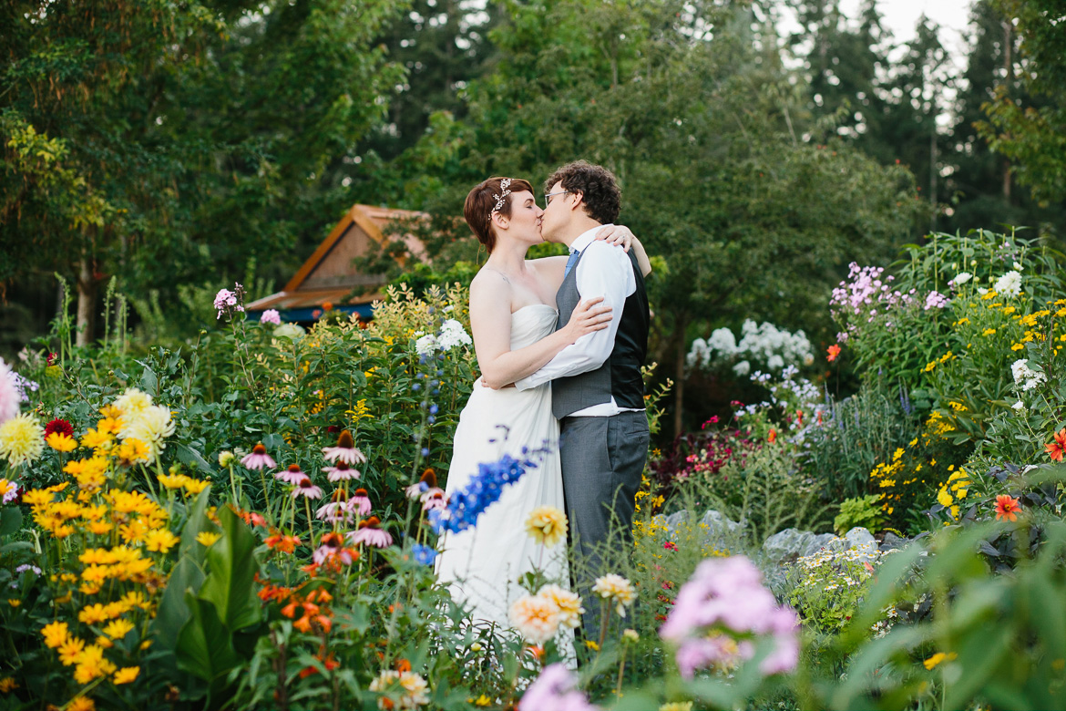 Bride and groom kissing in flowers during sunset at Fireseed Catering wedding on Whidbey Island, WA