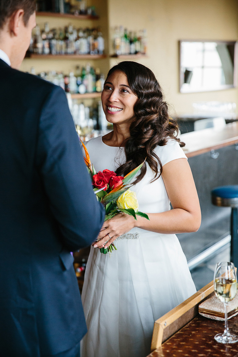 Bride smiling during groom's vows in a Pike Place Market elopement ceremony