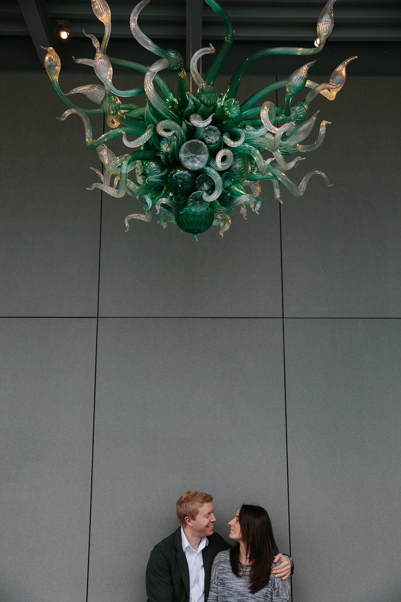 Couple sitting and smiling at Chihuly Garden and Glass engagement session in Seattle, WA