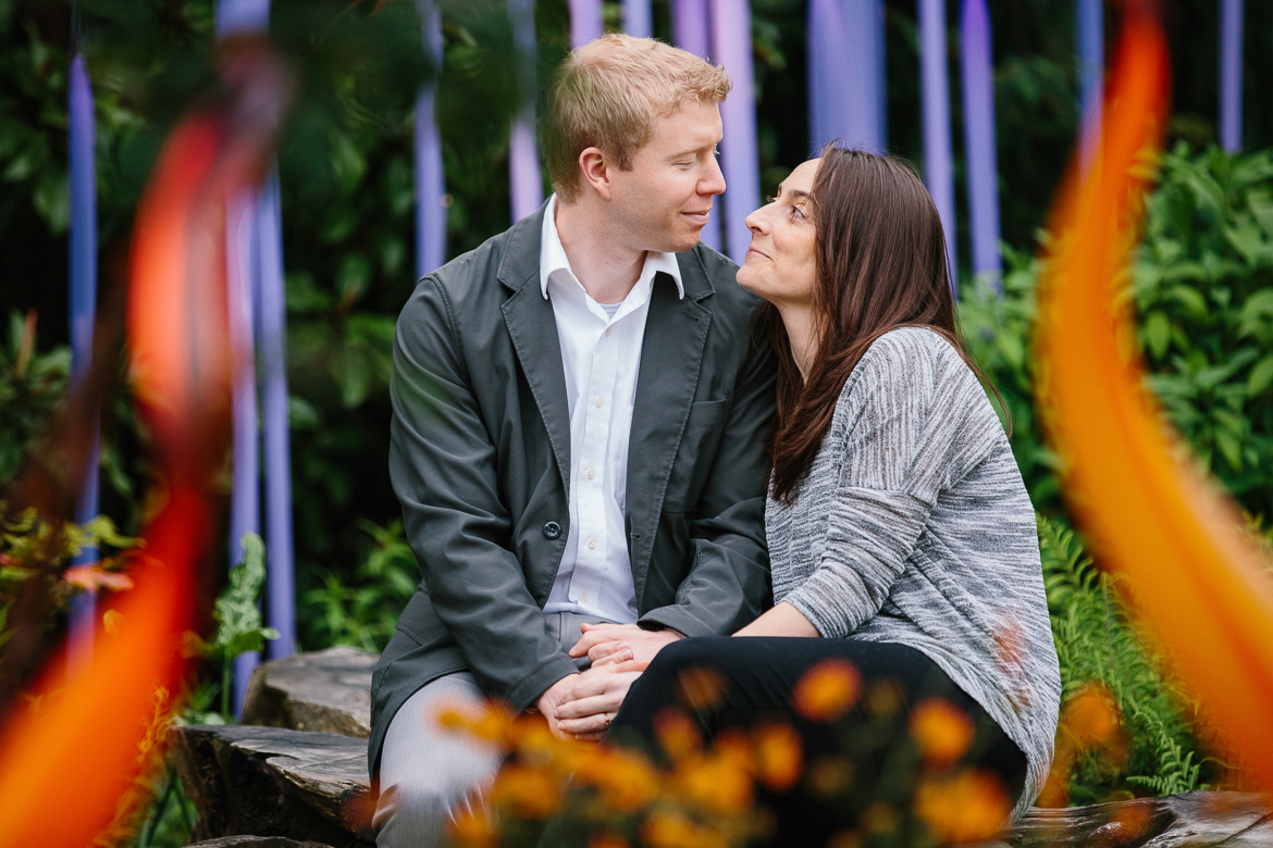 Couple sitting at Chihuly Garden and Glass engagement session in Seattle, WA