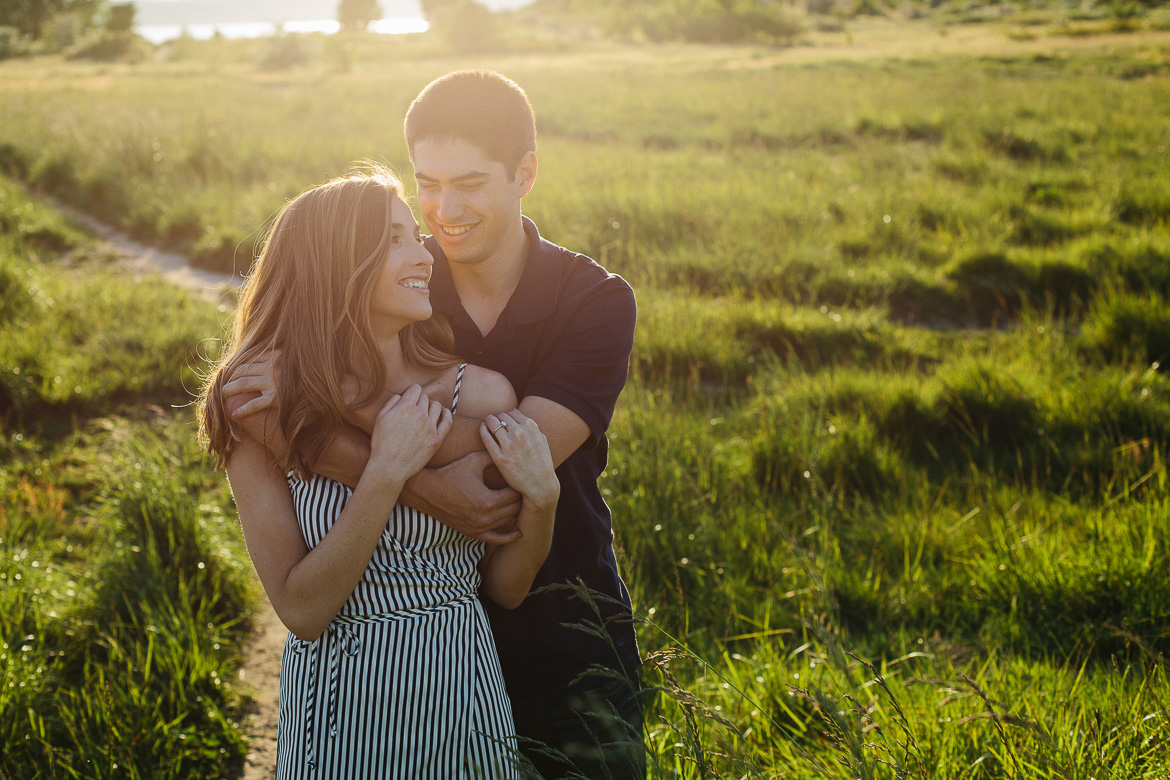 Couple laughing in field at sunset for engagement photos at Discovery Park in Seattle, WA
