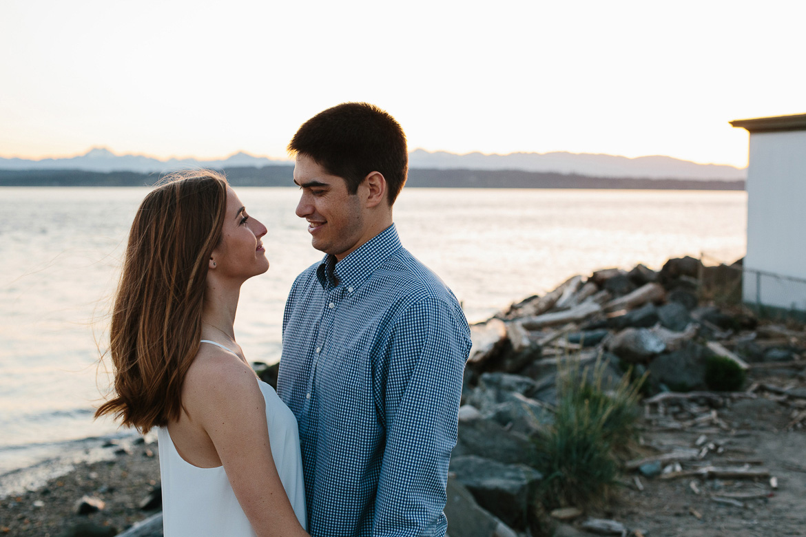 Couple on rocky beach during sunset engagement photos at Discovery Park in Seattle, WA