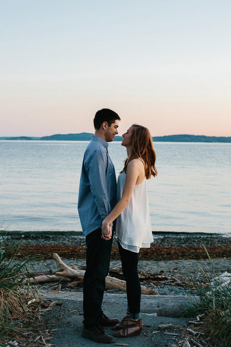 Couple in love on rocky beach during sunset engagement photos at Discovery Park in Seattle, WA