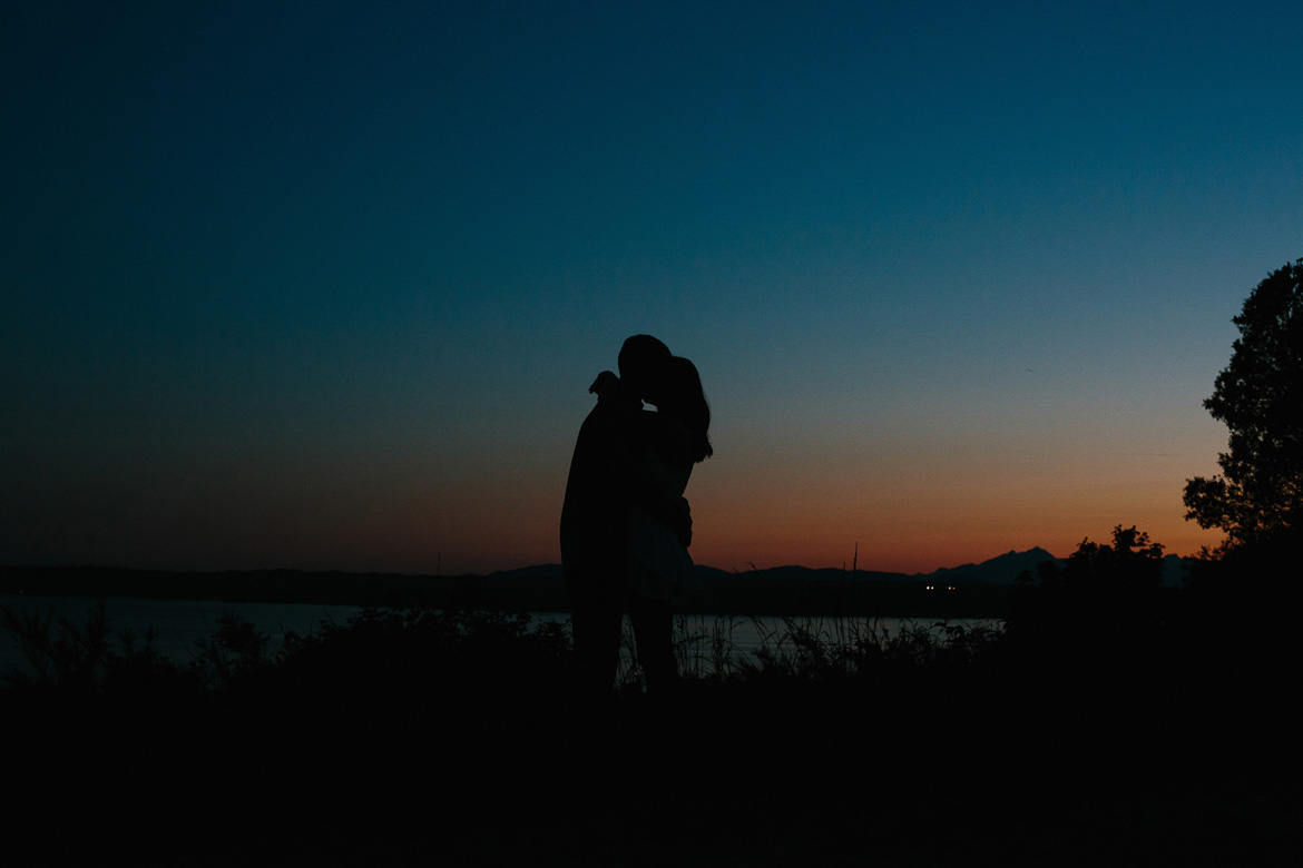Couple embracing during dusk engagement photos at Discovery Park in Seattle, Washington