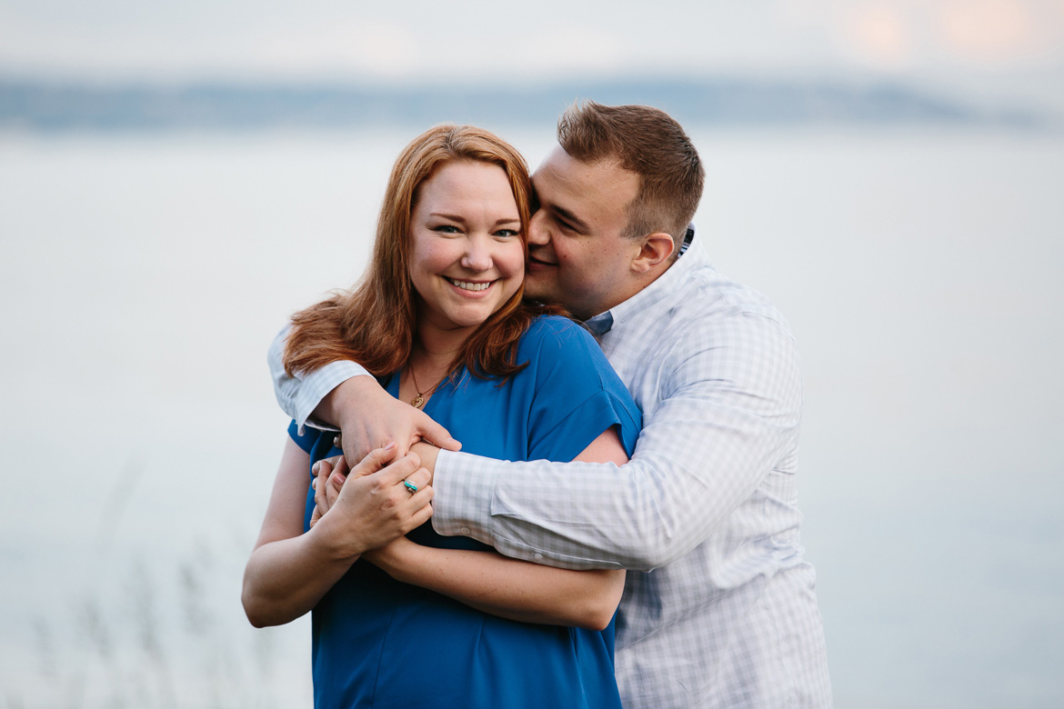 Couple laughing during sunset engagement photos at Discovery Park in Seattle, WA