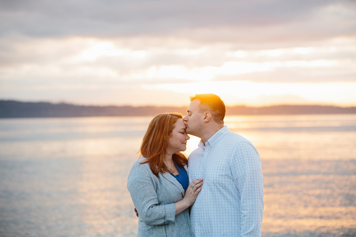 Couple kissing on beach during sunset engagement photos at Discovery Park in Seattle, WA