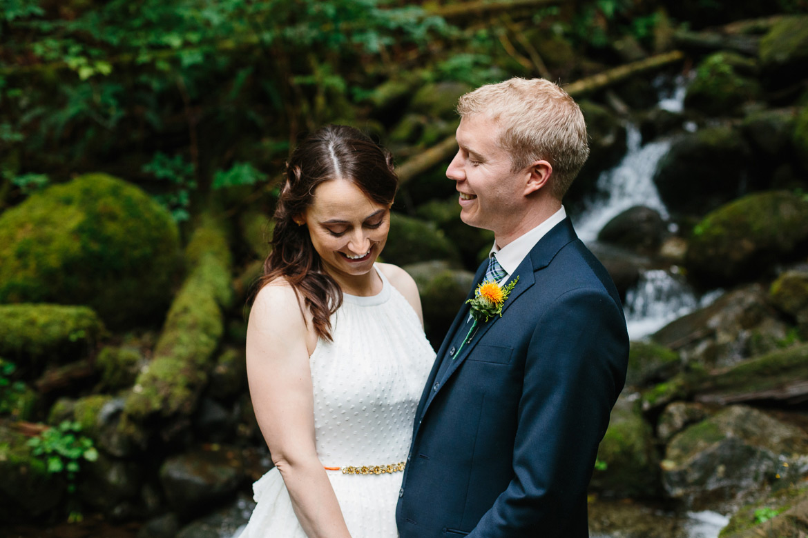 Bride and groom in front of waterfall during forest wedding portraits at Wallace Falls in Gold Bar, WA