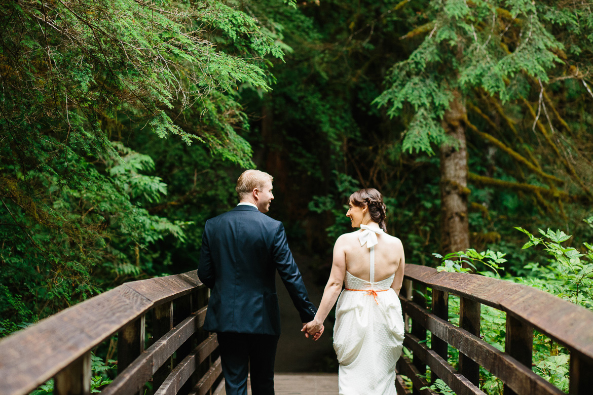 Bride and groom walking over bridge during wedding portraits at Wallace Falls State Park in Gold Bar, WA