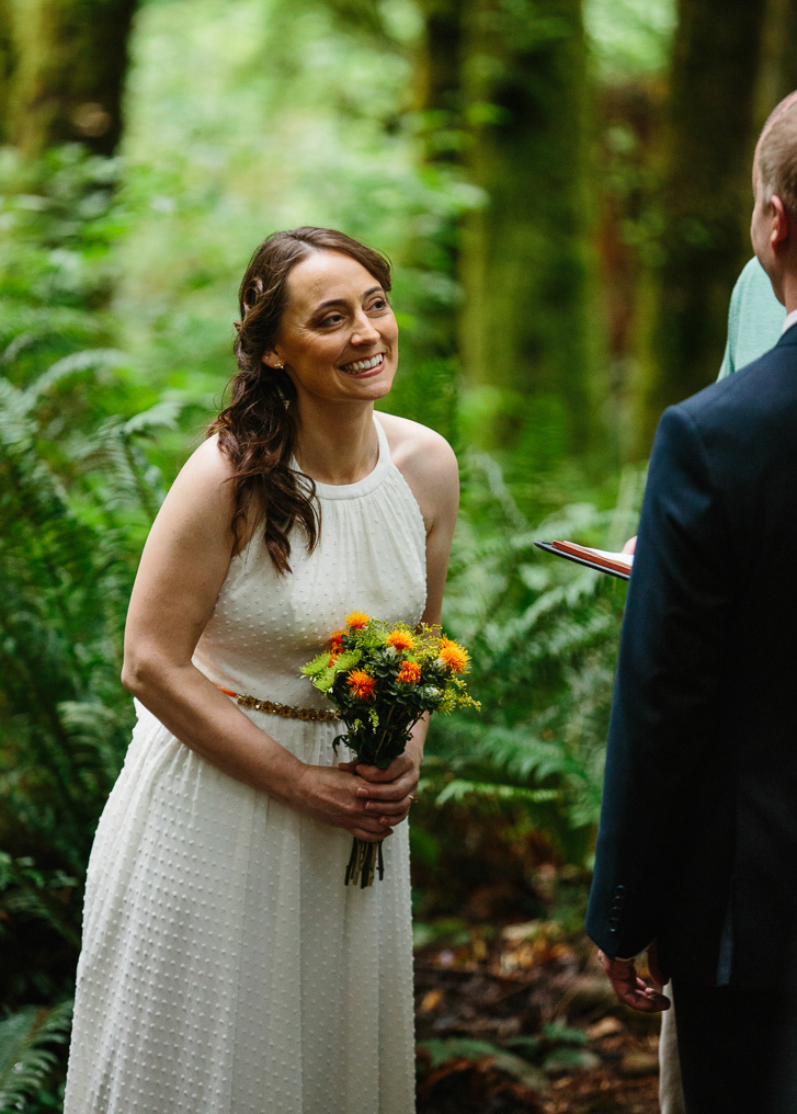 Bride laughing during forest wedding ceremony at Wallace Falls in Gold Bar, WA