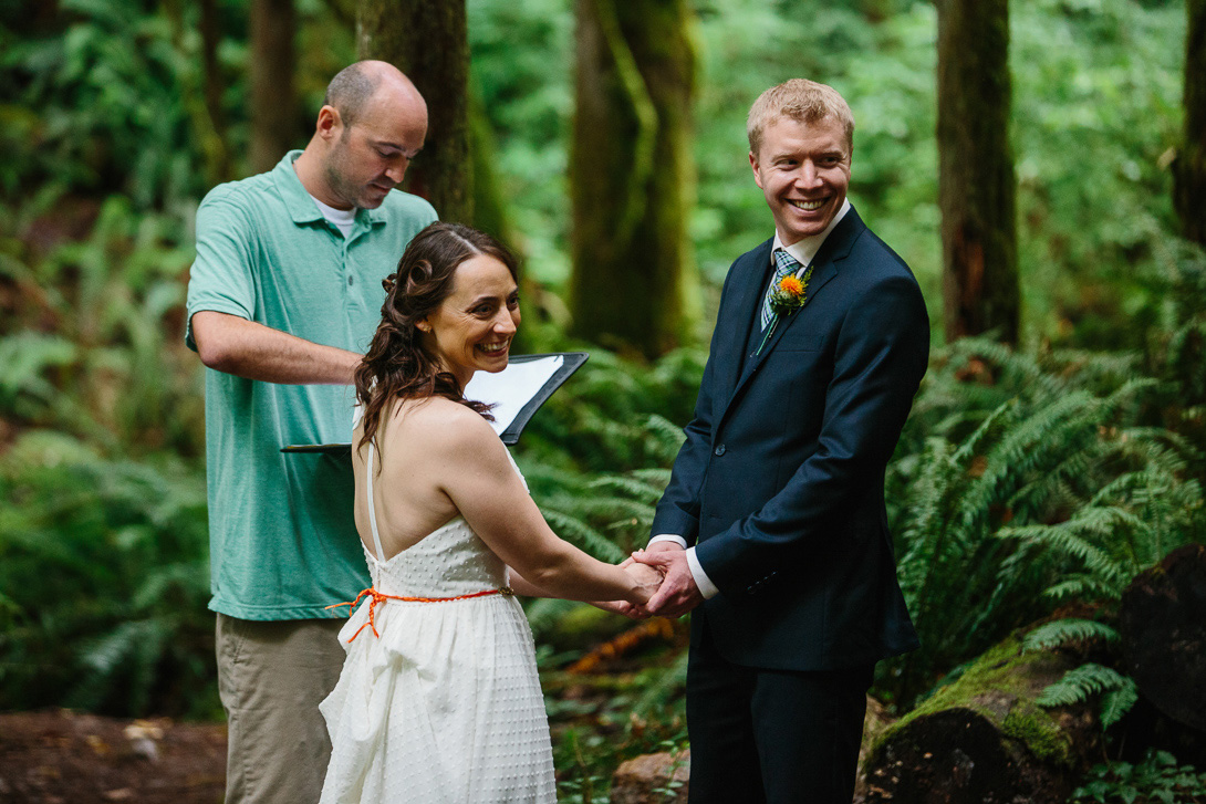 Bride and groom smiling during forest wedding ceremony at Wallace Falls in Gold Bar, WA