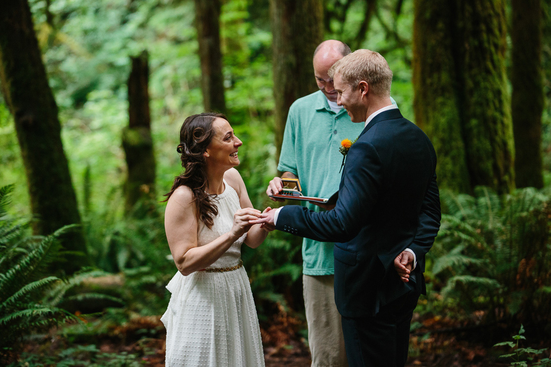 Bride laughing with ring during forest wedding ceremony at Wallace Falls in Gold Bar, WA
