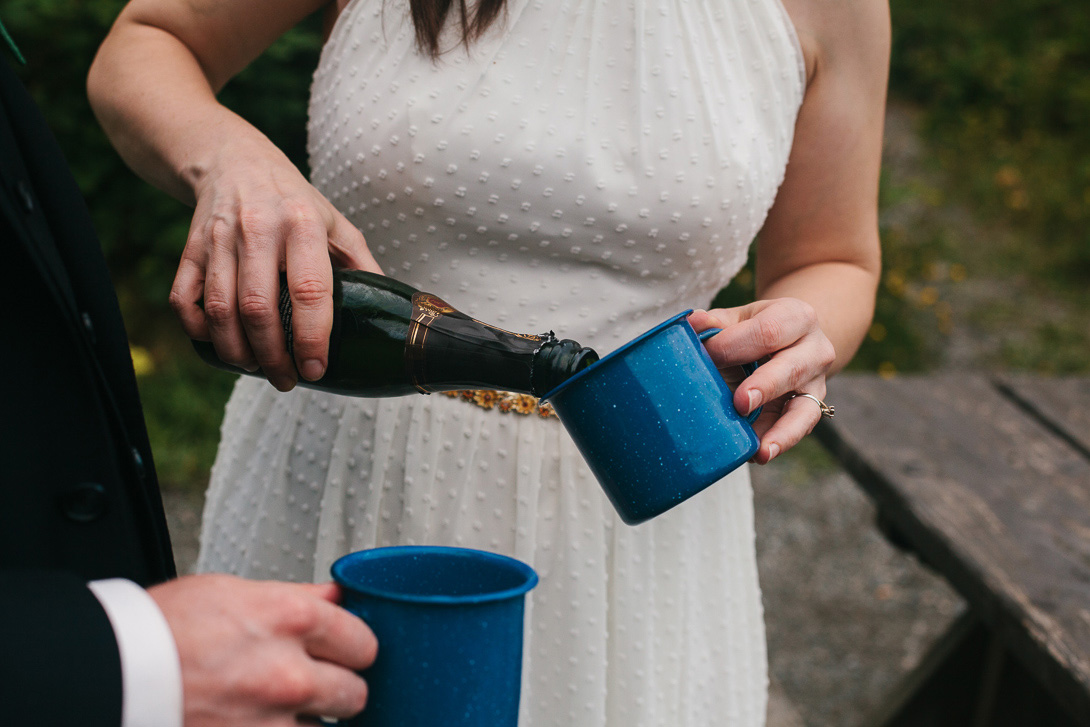 Bride pouring champagne during wedding portraits at Wallace Falls State Park in Gold Bar, WA