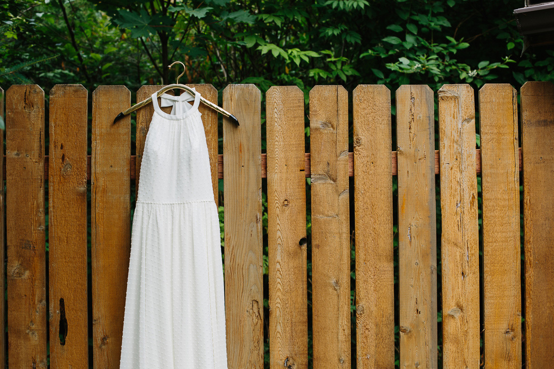 Wedding dress hanging on fence before wedding ceremony at Wallace Falls State Park in Gold Bar, WA