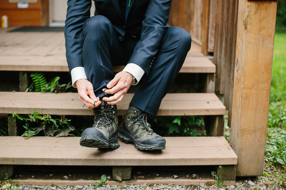Groom tying hiking boots before wedding ceremony at Wallace Falls State Park in Gold Bar, WA