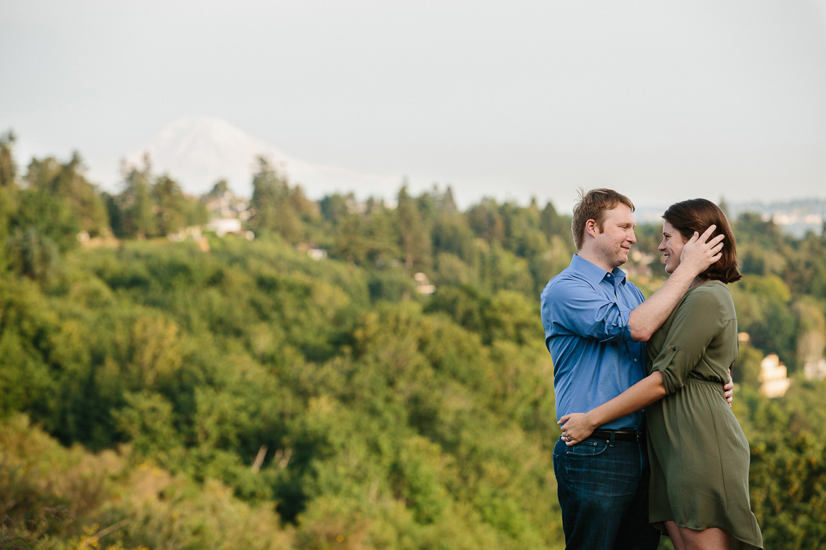 Couple smiling during sunset engagement session in Discovery Park in Seattle, WA with Mt Rainier