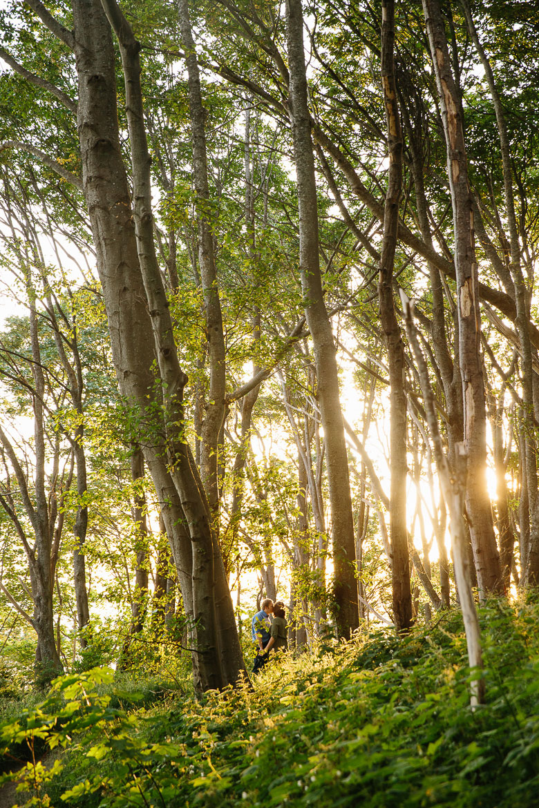 Couple kissing in forest during sunset engagement photos at Discovery Park in Seattle, WA