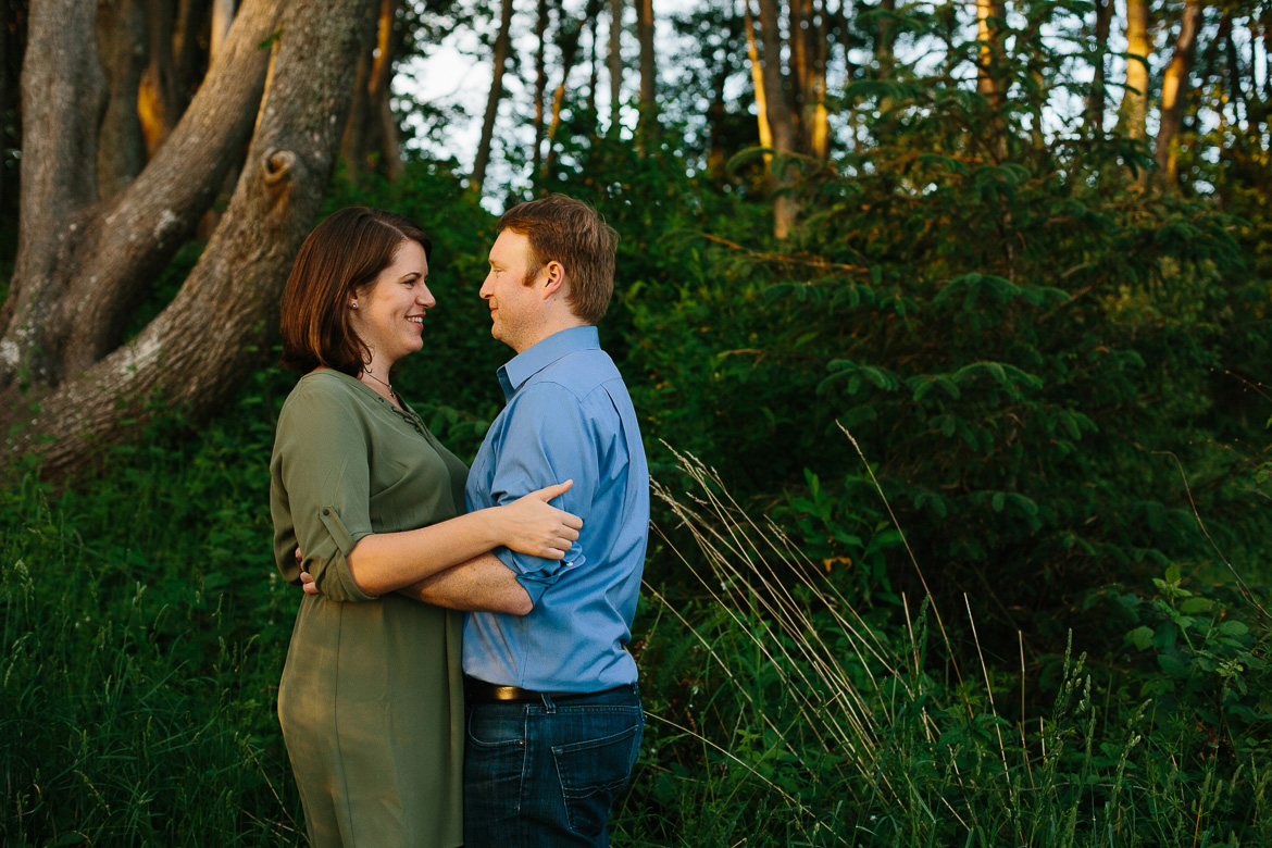 Couple smiling and holding each other during sunset engagement photos at Discovery Park in Seattle, WA