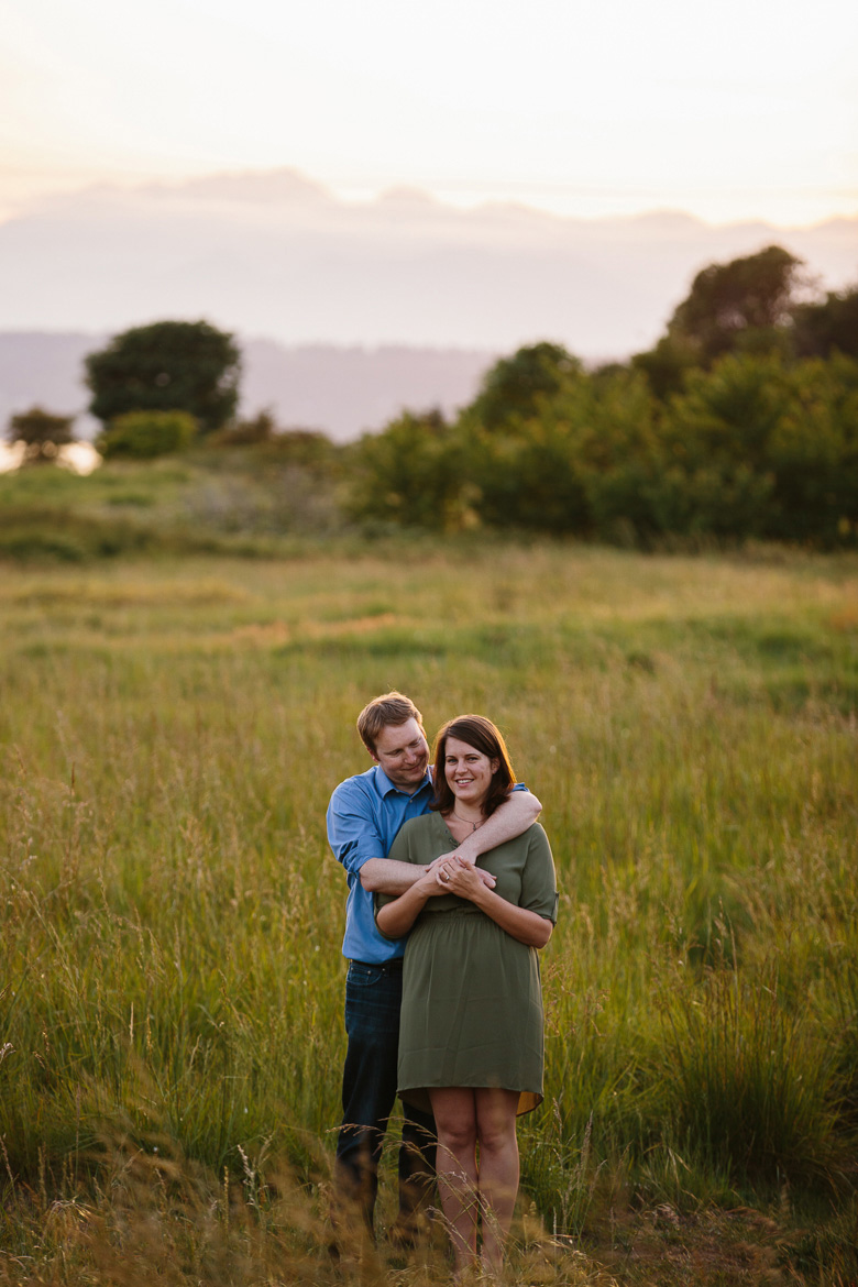 Couple standing in field during sunset engagement photos at Discovery Park in Seattle, WA