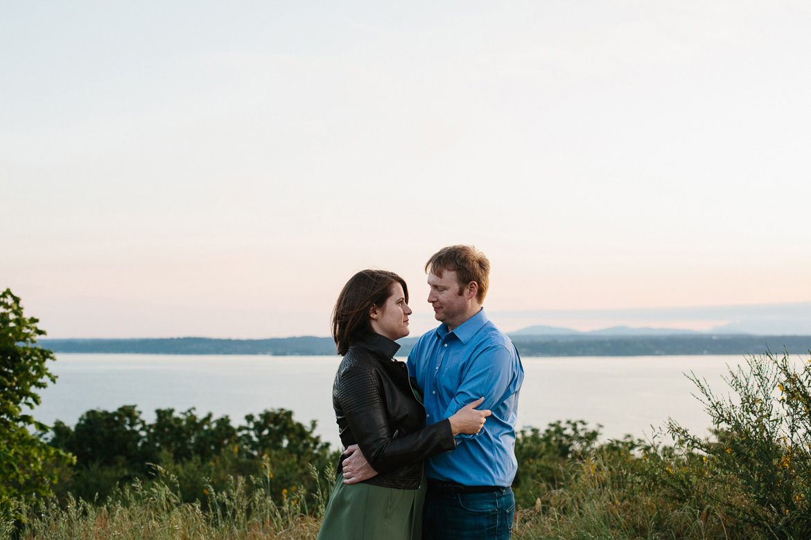 Couple holding each other during sunset engagement photos at Discovery Park in Seattle, WA