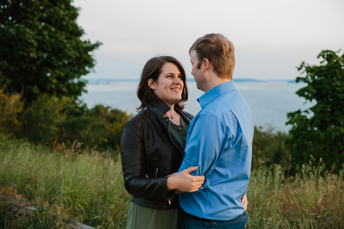 Couple smiling at each other during sunset engagement photos at Discovery Park in Seattle, WA