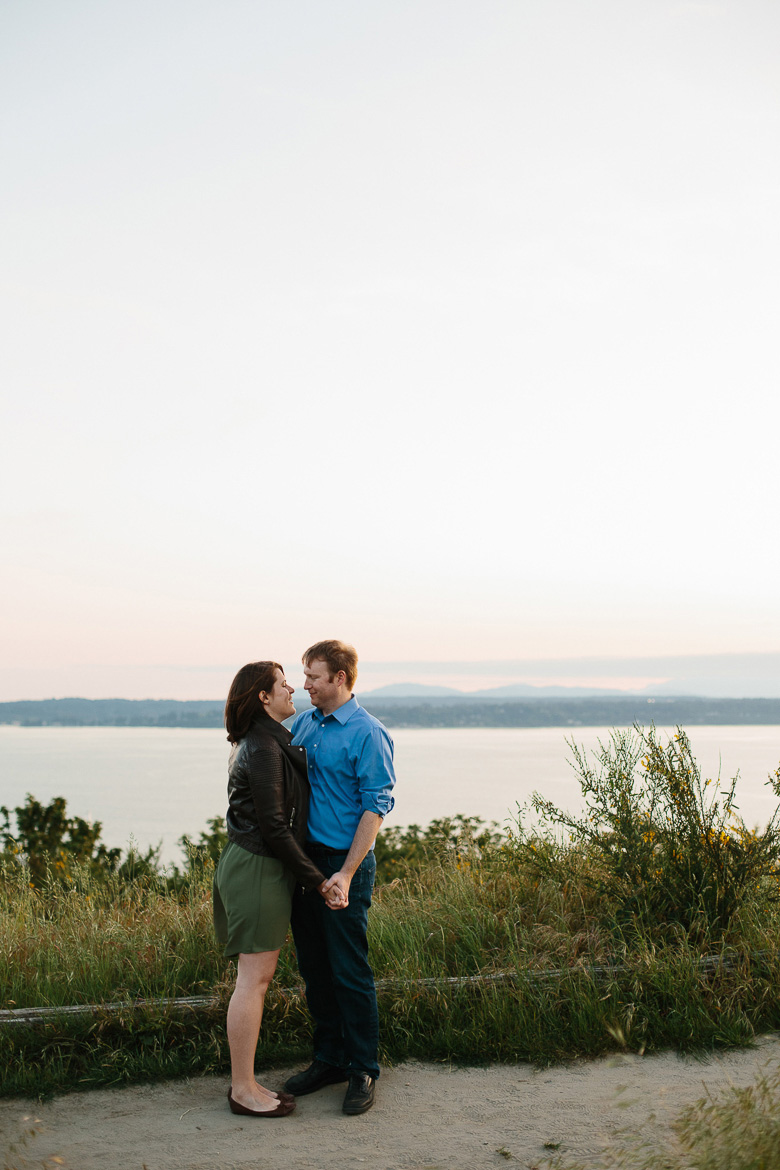 Couple smiling at each other during sunset engagement photos in Discovery Park in Seattle, WA