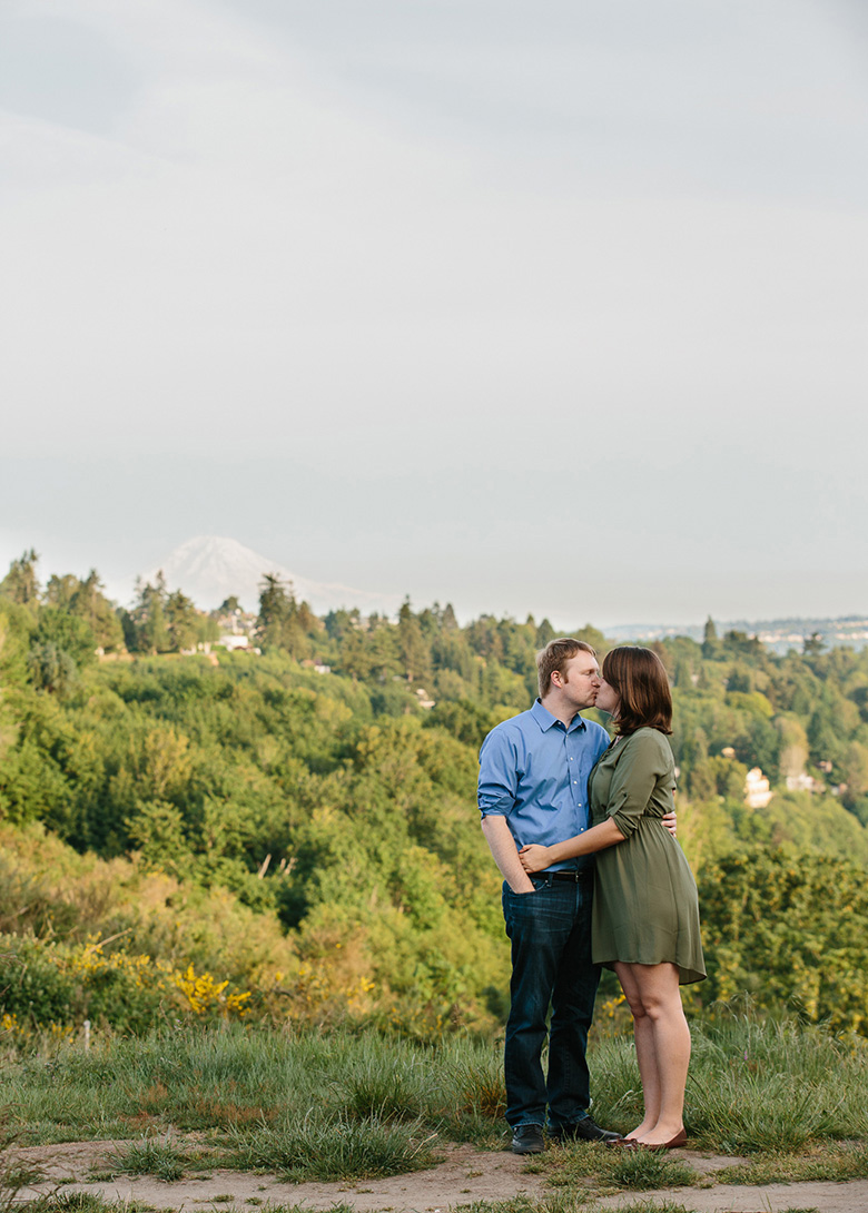 Couple kissing during sunset engagement session at Discovery Park in Seattle, WA with view of Mt Rainier