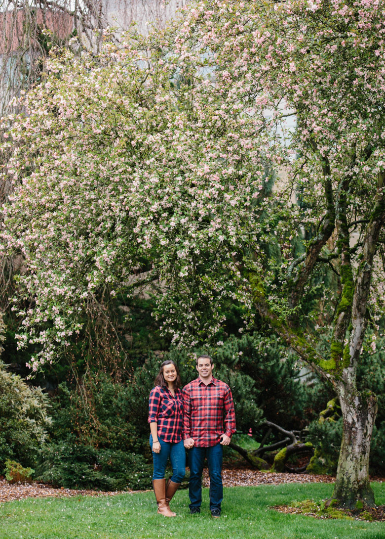 Couple standing under cherry tree during engagement photos at Seattle University in Washington