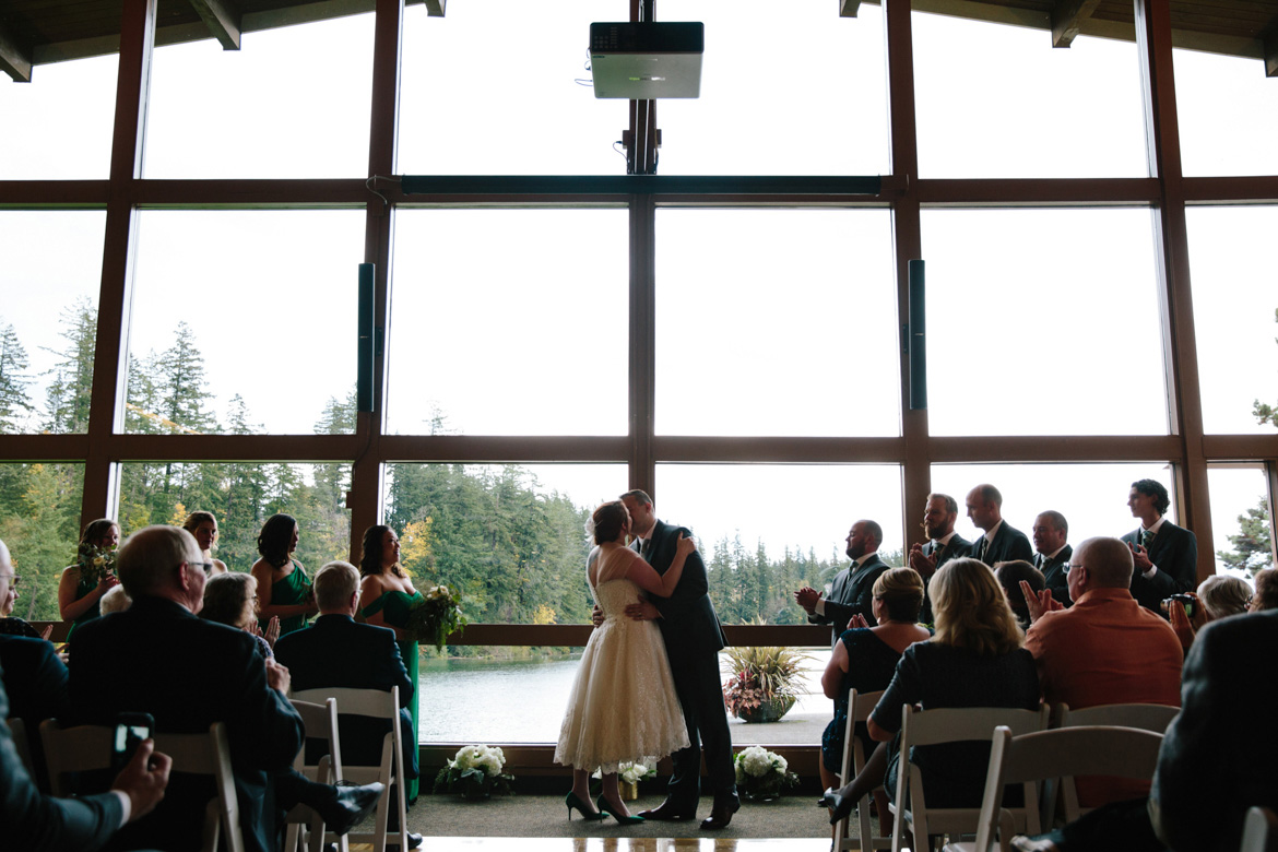 Bride and Groom sharing first kiss during wedding ceremony at Lake Wilderness Lodge in Maple Valley, WA