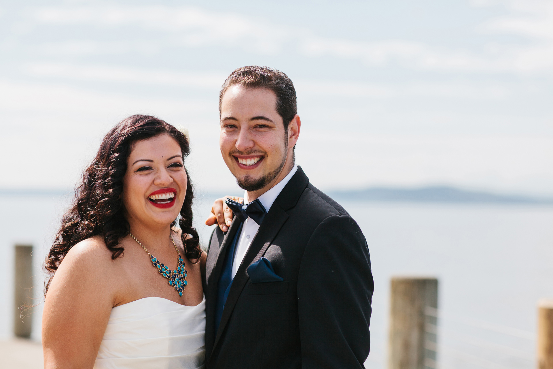 Couple laughing during portraits on Aliki Beach for Seattle wedding during wedding photography coverage