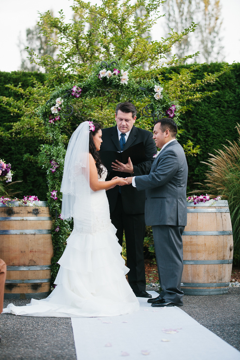Groom and bride exchanging rings during ceremony at Columbia Winery wedding in Woodinville
