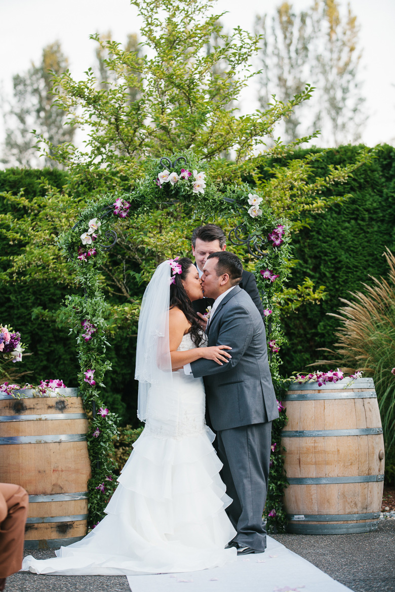 Groom and bride kissing during ceremony at Columbia Winery wedding in Woodinville