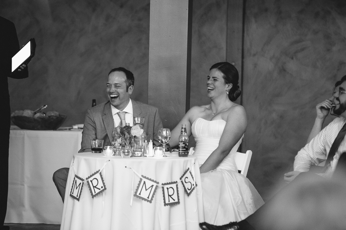 Bride and groom laughing during toasts during reception at Fireseed Catering on Whidbey Island