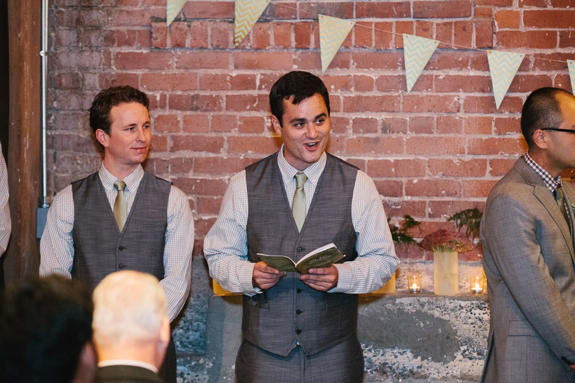 Groomsmen reading during wedding ceremony at Melrose Market Studios