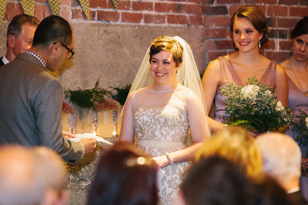 Bride during Grooms vows at wedding ceremony at Melrose Market Studios in Seattle, WA