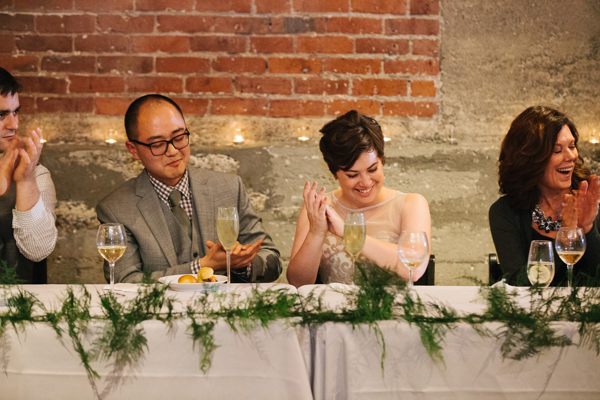 Bride and groom during reception toasts at Melrose Market Studios wedding in Seattle, WA
