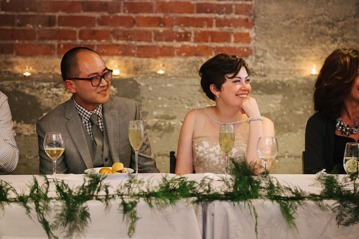 Bride and groom during reception toasts at Melrose Market Studios wedding in Seattle, WA