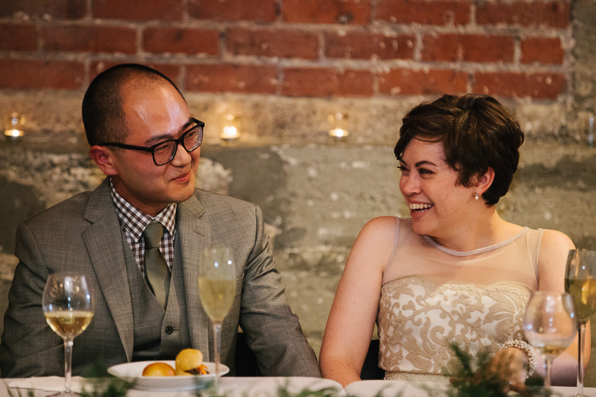 Bride and groom laughing during toasts during the reception at Melrose Market Studios wedding in Seattle, WA