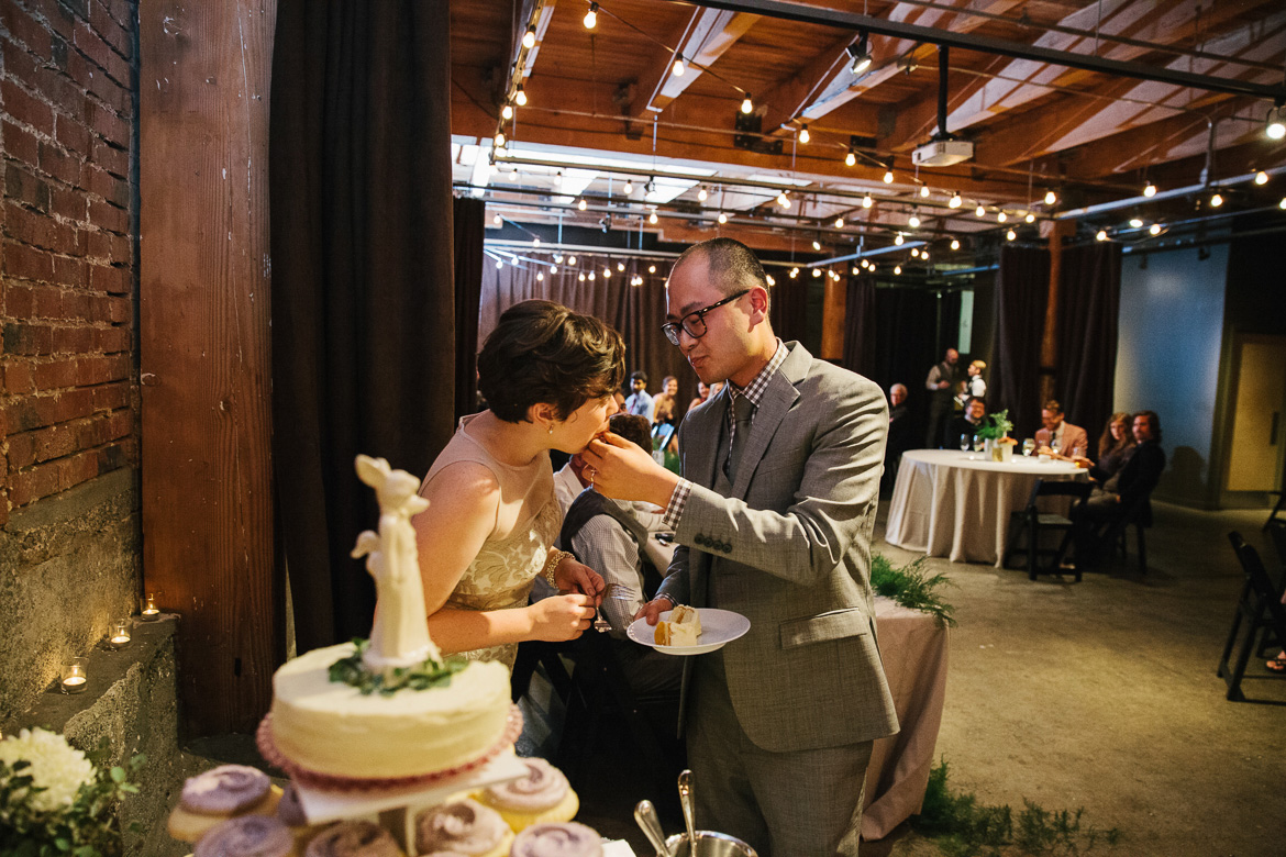 Bride and groom cutting the cake during wedding reception at Melrose Market Studios in Seattle, WA