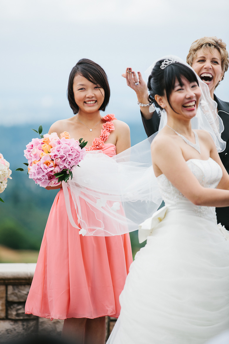 Bridesmaid and bride laughing during wedding ceremony at Newcastle Golf Course in Washington