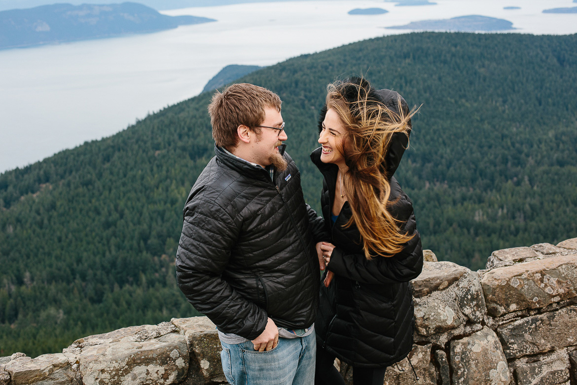 Couple laughing during windy engagement session on Mt Constitution in the San Juan Islands 