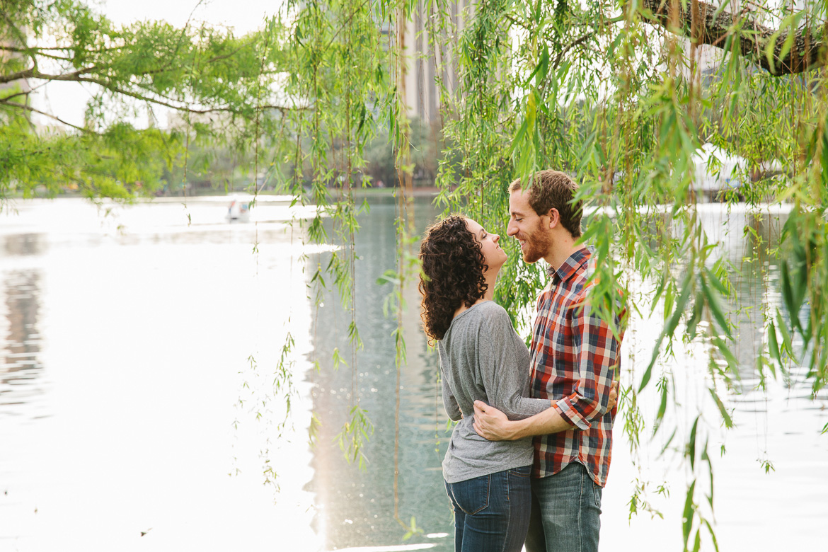 Couple laughing under willow tree during engagement photo session at Lake Eola Park in Orlando, FL