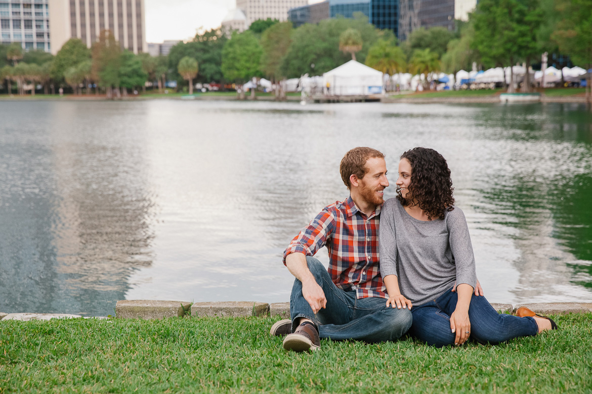 Couple sitting near water at Lake Eola Park in Orlando, FL during engagement photo session