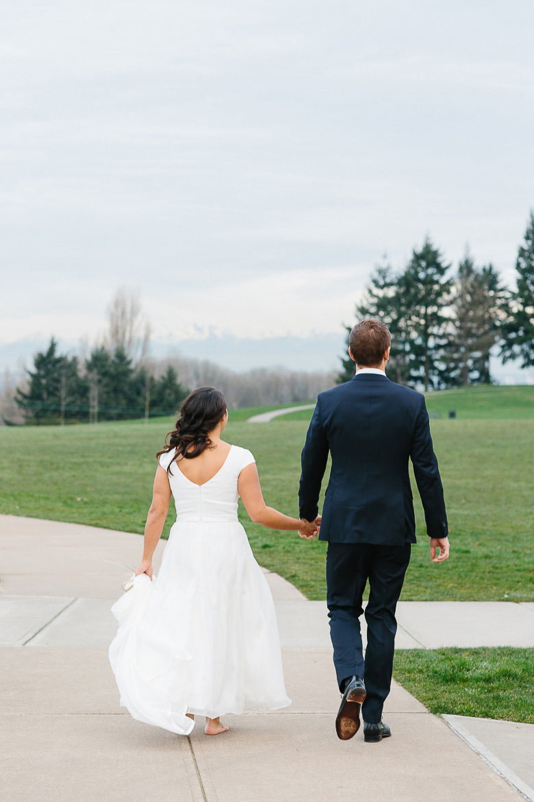 Bride and groom walking in Jefferson Park with Olympic Mountains in the distance