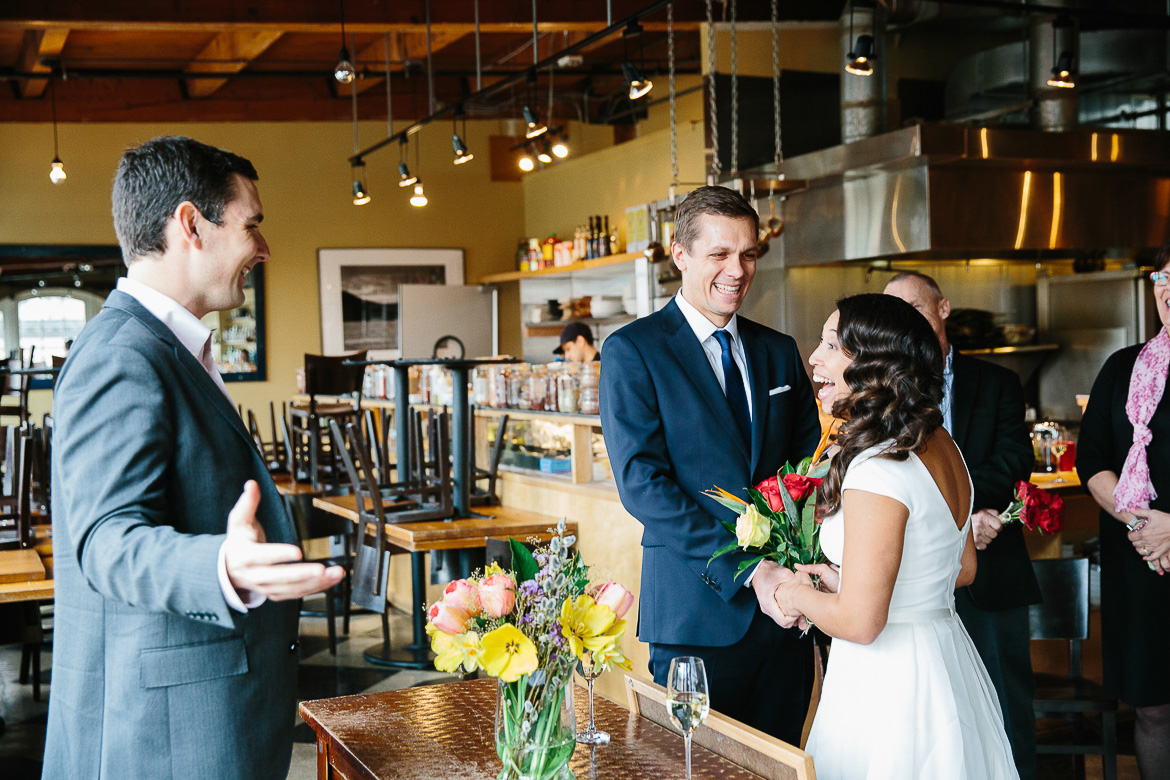 Bride, groom and officiant laughing during Pike Place Market elopement
