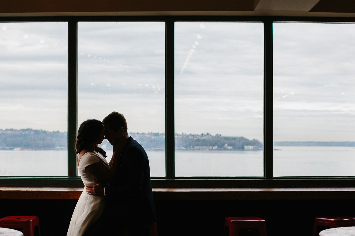 Bride and groom during photo session in Pike Place Market with view of water