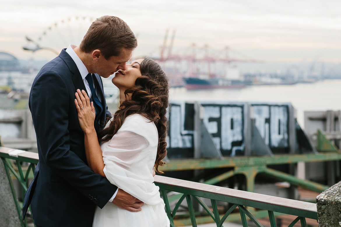 Bride and groom kissing with the Seattle waterfront behind them