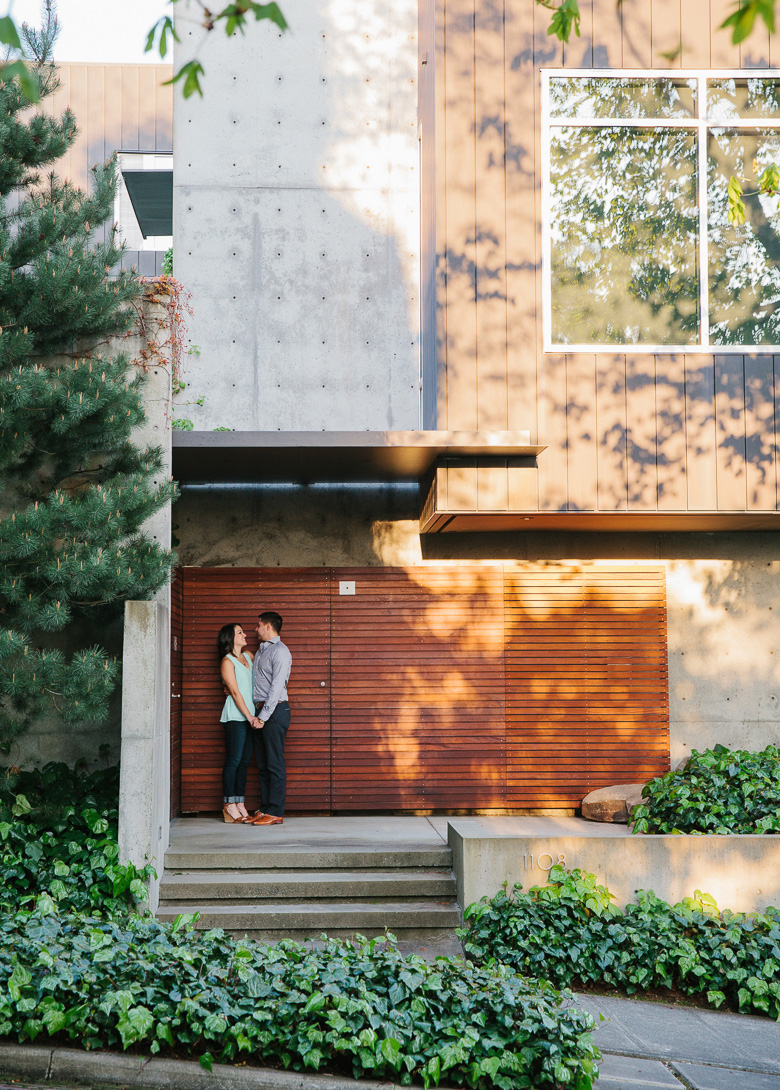 Seattle couple posing in front of modern house during sunset photo session on Upper Queen Anne